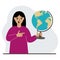 A woman holds a globe in his hand and points his finger at it. The concept of education, teacher, world conquest