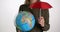 Woman holds globe and umbrella caring about saving planet