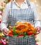 Woman holds golden roasted Christmas or Thanksgiving turkey