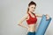 Woman holds in hand a mat for fitness sport slim figure exercises light background