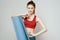 Woman holds in hand a mat for fitness sport slim figure exercises light background