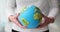 Woman holds in hands globe with bright green continents