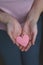 Woman holds in her hands carved pink heart cut out of paper. Authentic dark photography. Close-up. Congratulations or a surprise