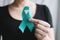 Woman holds in his hand Teal ribbon. Symbolic for cervical cancer, ovarian cancer, gynecological cancer and PCOS