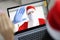 Woman holds laptop on screen santa claus in protective medical mask and gloves waving her hand