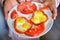 A woman holds a plate of quail eggs with tomato and bell pepper