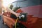 Woman holds plug of electric car charging station.