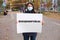A woman holds a poster with text, translated from Russian: Get vaccinated