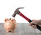 A woman holds a rusty hammer to smash a piggy bank on the wooden