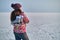 A woman holds skates on her shoulder after skiing on a frozen lake