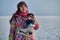 A woman holds skates on her shoulder after skiing on a frozen lake