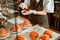 Woman holds small bowl with pink sprinklings above fresh decorated croissants on metal table