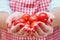 A woman holds small red tomatoes in her hands. Cook girl`s hands with ripe cherry tomatoes
