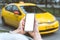 A woman holds a smartphone mockup in her hand, close-up. Against the backdrop of a taxi in the city