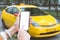 A woman holds a smartphone mockup in her hand, close-up. Against the backdrop of a taxi in the city