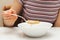 Woman holds a spoon and eating flakes with milk