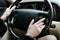 A woman holds the steering wheel of a luxury car.