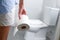 Woman holds toilet paper roll in front of toilet bowl