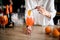 Woman holds tweezers with slice of orange over glass with drink.