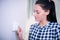 Woman At Home Adjusting Central Heating Thermostat Control