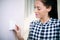 Woman At Home Adjusting Central Heating Thermostat Control