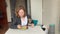 Woman at home with a dog sits eating at the table, a hungry puppy asks for food, licks his lips