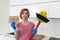 Woman at home kitchen in gloves with cleaning broom and mop asking for help