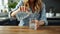 Woman at home sits at wooden table pouring water into glass, hydration lifestyle photo