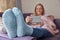 Woman At Home Wearing Cosy Warm Socks And Wrapped In Blanket Lying On Sofa Watching Digital Tablet