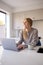 Woman At Home Working On Laptop On Counter In Kitchen 