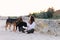 A woman and homeless dogs sits on a wild beach. freckles,dark curls hair