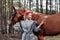 Woman on a horse in the fall. Creative bright pink makeup on the girl face, hair coloring. Portrait of a girl with a horse. Horseb