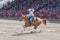 Woman and horse gallop to second barrel at barrel racing competition