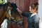 Woman with horse in stable at countryside ranch. Girl horse rider in summer outdoor. Equestrian and horseback riding. Horse