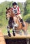 Woman on horseback jumping in water drops