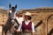 Woman horsewoman, young and beautiful, with stick and hat, next to her horse, in the countryside next to a ruined building.