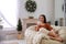 Woman with hot drink resting in comfortable papasan chair at home. Space for text