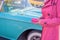 Woman in hot pink rain coat holding wallet looking at a baby blu