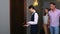 Woman hotel manager walks down the corridor and opens door of room for couple.