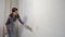 Woman house painter is painting wall using brush doing renovation at home.