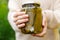 Woman housewife hand holding glass jar of pickled cucumbers. Domestic preparation pickling and canning of vegetables