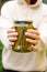 Woman housewife hand holding glass jar of pickled cucumbers. Domestic preparation pickling and canning of vegetables