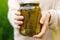 Woman housewife hand holding glass jar of pickled cucumbers. Domestic preparation pickling and canning of vegetables, winter