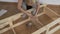 Woman housewife sitting in the room on the floor, collects wooden rack, bought in the store. Assembly of furniture.