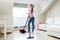 Woman or housewife with vacuum cleaner at home