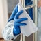 Woman Houseworker in rubber blue gloves clean Door knob by cloth rag. Cleaning front door handle by antibacterial alcohol spray.