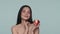 A woman with hydrogel red patches under her eyes tosses a ripe apple from one hand to the other. Seminude brunette woman