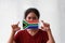 A woman and hygienic mask with South Africa flag pattern in her hand and raises it to cover her face. A mask is a very good