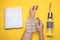 Woman with ice pack, bottle of water and towel on yellow background, top view. Heat stroke treatment