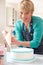 Woman Icing Birthday Cake In Kitchen At Home